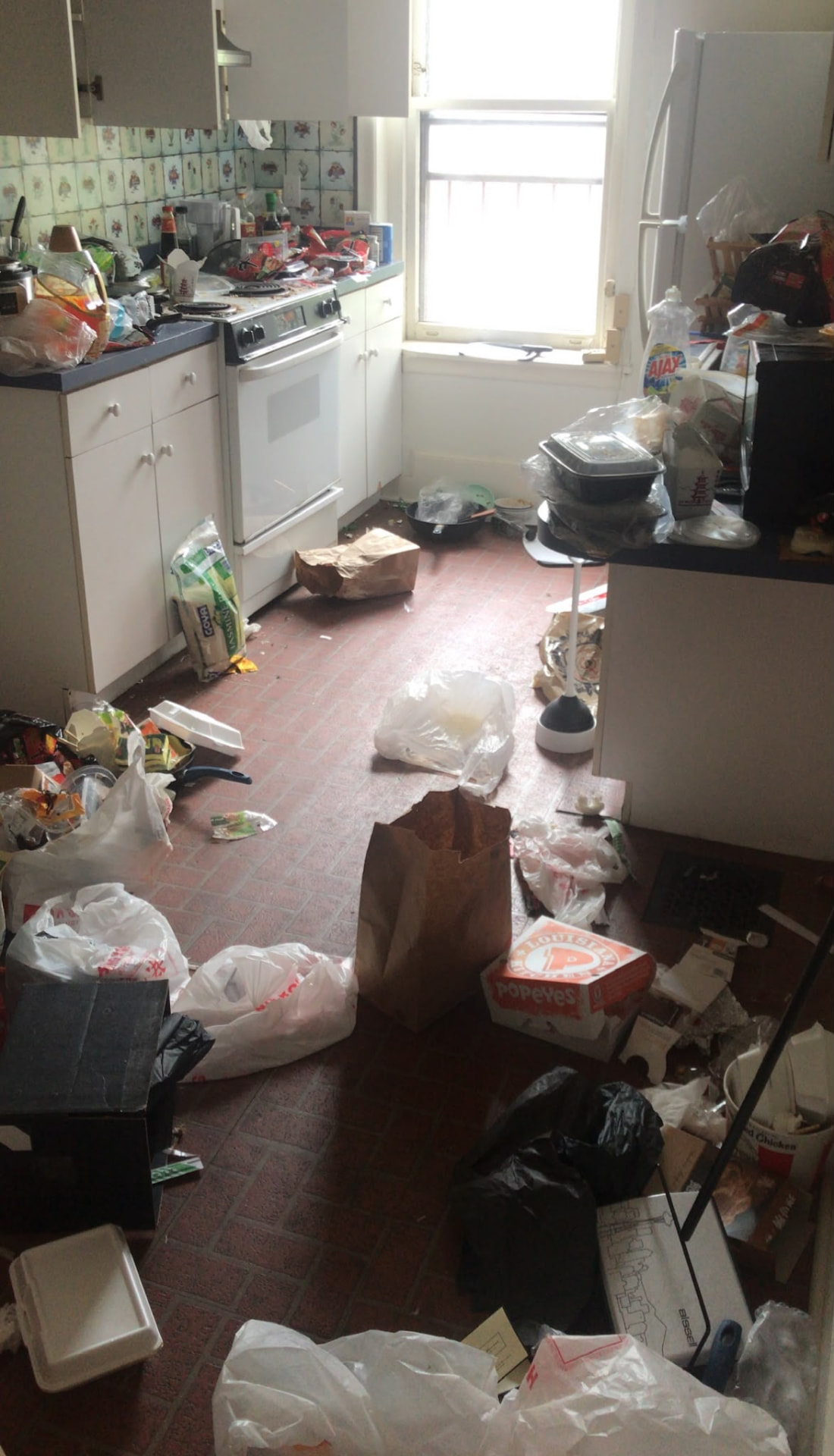 Kitchen before cleaning, covered in trash and clutter